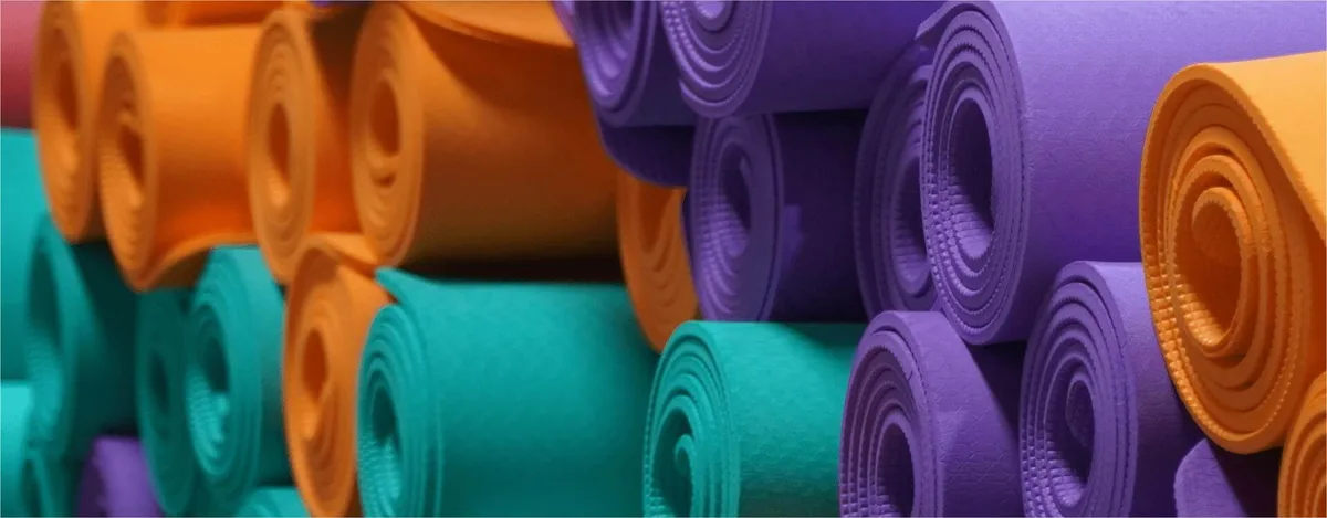 A stack of rolled yoga mats in many colours